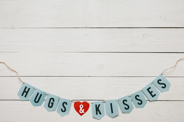 Hugs and kisses banner garland nice inscription on white barn wood planks background. Red paper heart. Space for copy, text, lettering, Valentines day holiday postcard template.