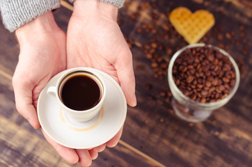White coffee cup and coffee beans on old wooden background.
