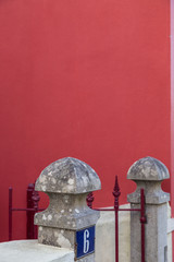 stone decoration on pillar of fence on red wall