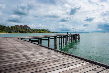 Obraz premium Beautiful Wooden Jetty with Dramatic Sky and Green Island Backg