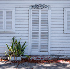 old wooden white door  and window on a white wooden wall with a small plan growing close to it. Miami. Bahia Honda Park. Florida. USA.