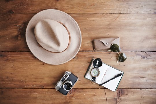 Planning next trip on table whith vintage camera, compass, sunglasses and hat.