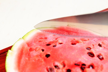 Cutting board with a knife and ripe watermelon.