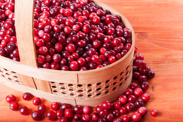 Wooden basket with fresh red cranberries on a wooden background