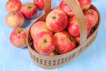 Basket with apples on a wooden background.
