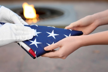 Hands holding folded American flag on Eternal flame background