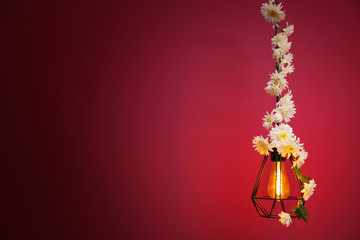 Lamp decorated with flower garland on purple background