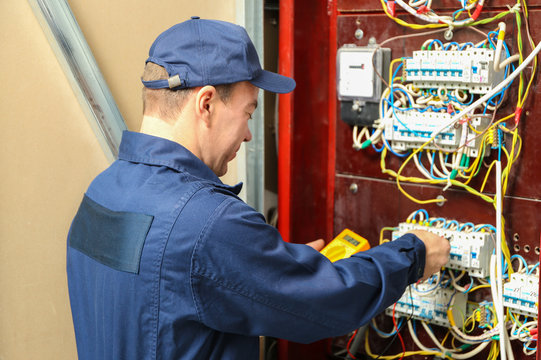 Electrician measuring voltage in distribution board