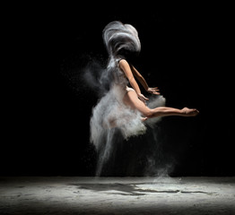 Fototapeta na wymiar Young girl dancing in white dust color in studio