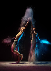 Fototapeta na wymiar Sporty couple in color dust cloud studio shot