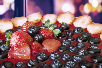 Delicious cake with berries on bokeh background
