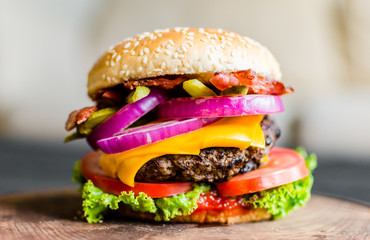 Burger on a wooden table against black background. Selective focus