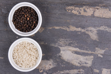 Course gray salt and peppercorns in smal ramekins on gray slate