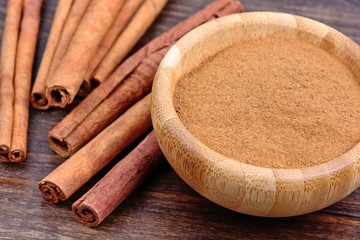 Cinnamon sticks and bowl with cinnamon powder on table