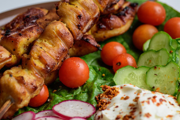 Chicken kebab with vegetables on a clay plate