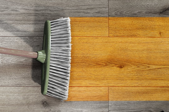 sweeping wooden floor with broom