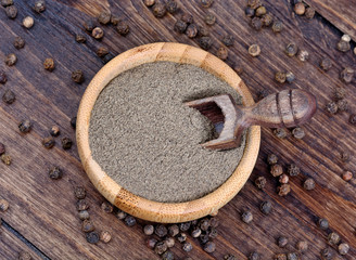 Bowl with black pepper on wooden background