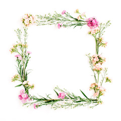 Obraz na płótnie Canvas Wreath frame made of pink and beige wildflowers, green leaves, branches on white background. Flat lay, top view. Valentine's background