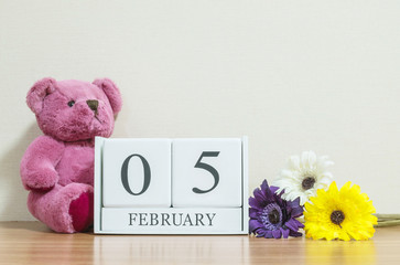 Closeup surface white wooden calendar with black 5 february word on brown wood desk and cream color...