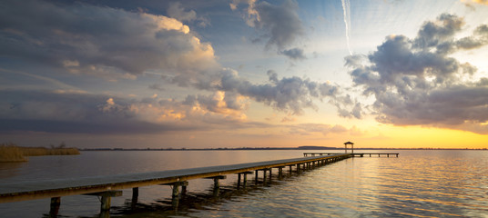 houten pier met uitzicht op het meer, de prachtige avondlucht, gekleurd door de ondergaande zon