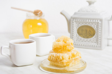 Honey with honeycomb and tea with teapot on the background