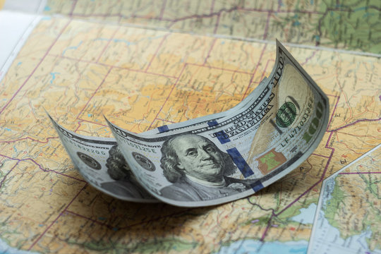 Нundred dollar bill on the U.S. map, money for travel, backgrou