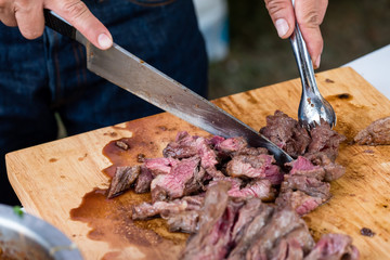 chef's hand using knife to cut grilled beef