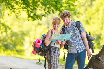 Hiking backpacking couple reading map on trip.