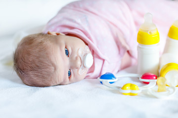 Cute newborn baby girl with nursing bottles and pacifier