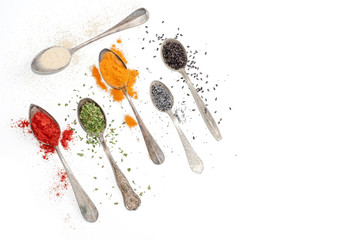 spices on silverware spoons and white background