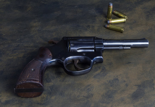 Six shooter loaded gun, .38 caliber handgun with wood grip and brass flat head bullets isolated on dark grunge background