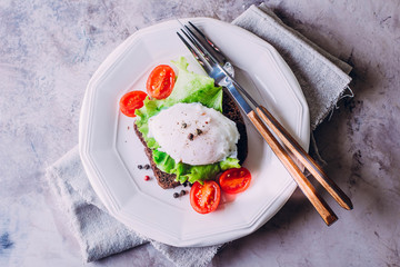 Rye Bread Toast and Poached Egg with Green Salad, Cherry tomato, cup of coffee and Orange Juice on the Wooden Table Background. Healthy Breakfast content