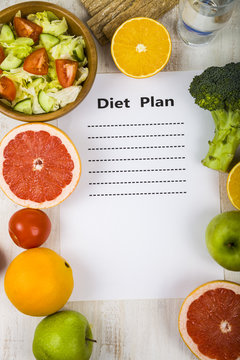 Food and sheet of paper with a diet plan on a  wooden table. Con