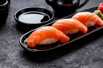 Fotobehang Salmon sushi with soy sauce on a black plate and dark concrete background. © z10e