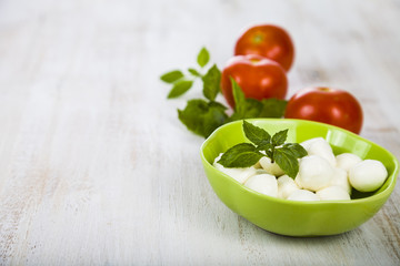 Mozzarella in a green plate on a wooden table. Mozzarella balls