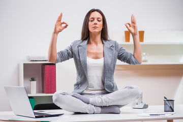 Young businesswoman is meditating in her office. 