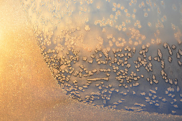 Winter background. Frosty pattern on window glass closeup in the sunlight.