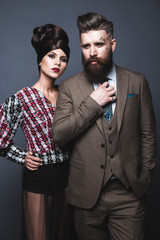 Couple, man and woman in evening dresses posing for studio photo shoot