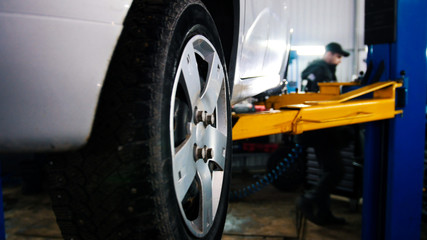 Fototapeta na wymiar Car in auto service lifting for repairing, mechanics in garage