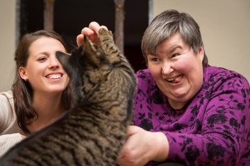 geistig behinderte Frau spielt mit einer Katze, Tiertherapie