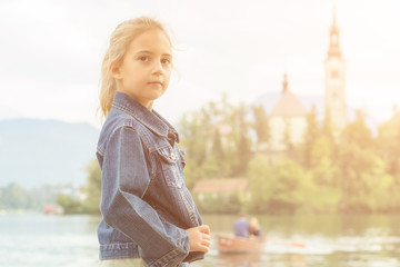 Fototapeta na wymiar Little girl standing on a pier near the lake.