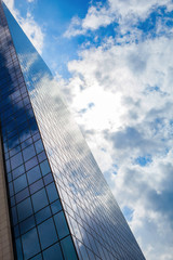 Fototapeta na wymiar Modern smoked glass office building against a blue cloudy sky.