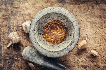 Spicy crushed peppers in a granite mortar.