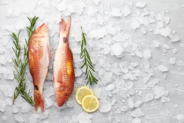 Wall murals Fish Fresh red mullet fish with lemon and rosemary on icy stone background