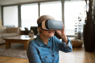 Senior woman wearing virtual reality goggles at home