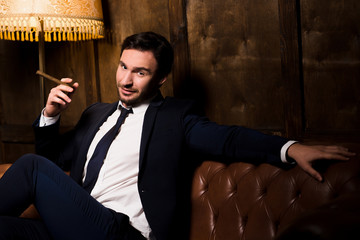 Successful baron sitting on sofa and looking at camera while spending time in restaurant. Handsome...