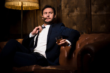 Millionaire man resting and relaxing while sitting on sofa in restaurant or men's club. Handsome...