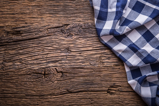 Top view of checkered tablecloth or napkin on empty wooden table.