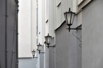 Narrow alley with old wall lanterns in perspective.