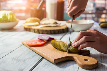 Knife cutting pickled cucumber. Sliced vegetables on wooden board. Ingredient for salty salad.